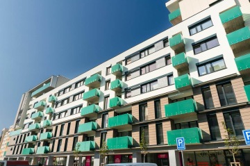 Moderní bytový dům BD Smart s prosklenými balkony a modrou oblohou.