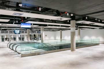 Moderní interiér s prázdným prostorem, celoskleněným zábradlím a eskalátory v nákupním centru.