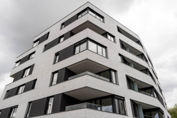 Moderní bytový dům s balkony s celoskleněným zábradlím.