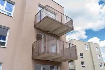 Moderní bytový dům Modřanský Cukrovar s balkony a modrou oblohou.