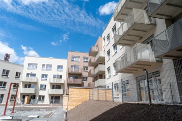 Moderní bytový komplex Modřanský Cukrovar s balkonem a modrou oblohou.