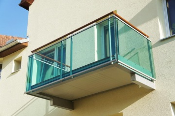 Moderní balkon Dolní Kounice s průhledným skleněným zábradlím na fasádě domu.