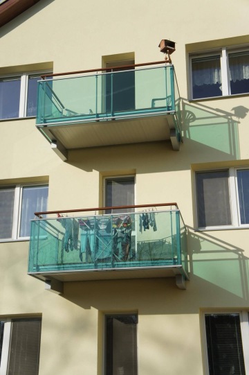 Bytový dům Dolní Kounice se dvěma balkony se skleněným zábradlím, na dolním sušící se prádlo.