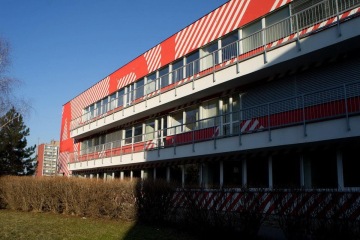 Budova s balkony s kovovým venkovním zábradlím.