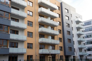 Moderní bytový komplex s balkony a okny v různých barvách.