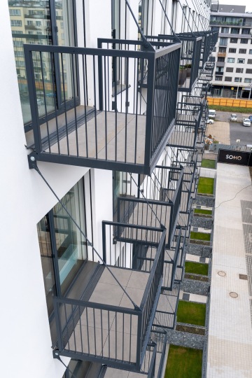 Moderní balkóny v řadě na fasádě budovy, výhled na městské prostředí.