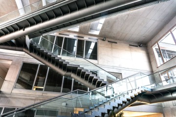 Moderní architektonické schodiště Jihočeské Univerzity s kovovými a skleněnými prvky uvnitř budovy.