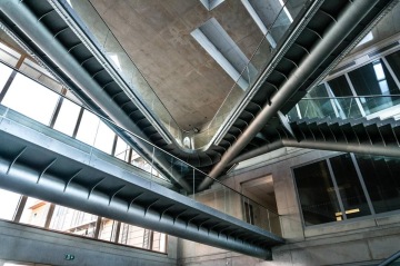 Moderní interiér Jihočeské Univerzita s kovovými schodišti a prosklenými zábradlími v industriálním stylu.