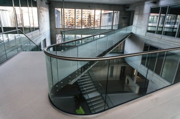 Moderní interiér Jihočeské Univerzita s otevřeným schodištěm a skleněným zábradlím, výhled na městskou architekturu.