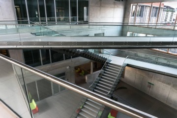 Moderní interiér Jihočeské Univerzita se schodištěm a proskleným zábradlím, kancelářské budovy na pozadí.