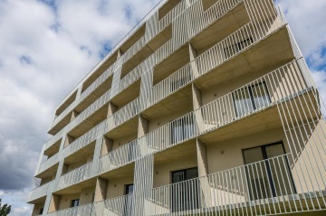 Moderní bytový dům BD Krejcárek s balkóny a kovovým zábradlím pod modrou oblohou.