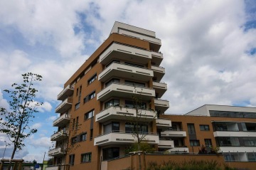 Moderní bytový dům BD Nad Modřanskou s balkony a světlou fasádou pod zamračenou oblohou.