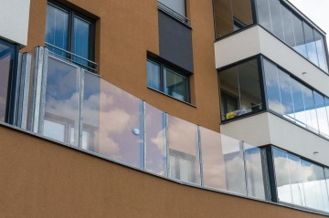 Moderní balkony BD Nad Modřanskou s průhledným sklem na fasádě vícepatrové budovy.
