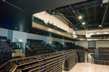 Moderní prostorný sál O2 Universum Praha s prázdnými stupňovitými sedadly a osvětlením.