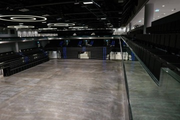 Moderní prázdná hala O2 Universum Praha s kruhovým osvětlením a sklopenými sedadly.