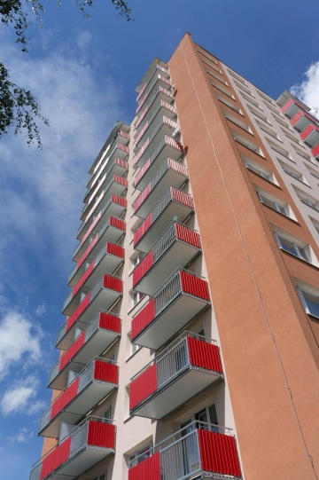 Vyškový bytový dům s červenými závěsnými balkony.