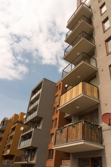 Moderní bytové budovy s balkony pod modrou oblohou.