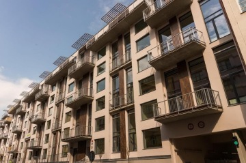 Moderní bytový dům X Loft s balkony a velkými okny pod modrou oblohou.