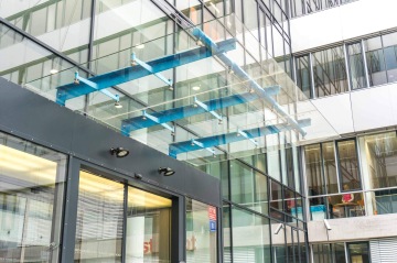 Moderní prosklená kancelářská budova Kavčí Hory s modrými kovovými prvky a panoramatickými okny.