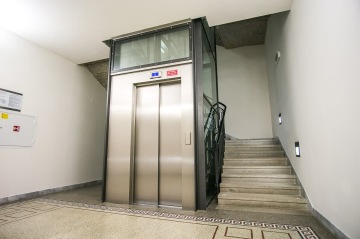 Výtah s nerezovým obložením a prosklenou výtahovou šachtou.