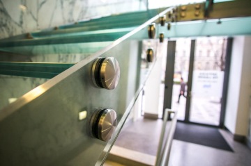 Skleněné schodiště s kovovými prvky vedoucí k prosklenému vstupu budovy.