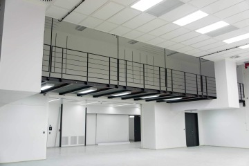 Moderní průmyslový interiér Laserové centrum ELI s bílými stěnami a černým kovovým podlažím.