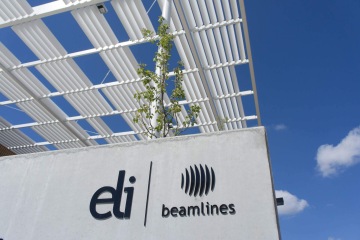 Budova ELI Beamlines se stínící konstrukcí, obloha je jasně modrá.