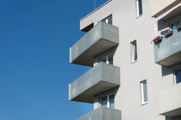 Moderní bytový dům BD Zahrady Opatov s kovovými balkony proti modré obloze.
