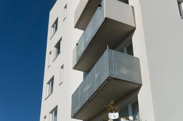 Moderní bytový dům BD Zahrady Opatov s několika balkony za slunečného dne.