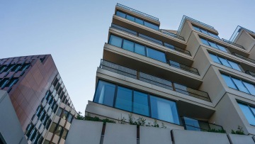 Moderní bytové domy BD 4U Living s velkými okenními tabulemi a balkony, pohled zespodu na modrou oblohu.