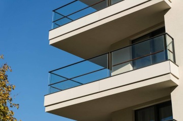 Balkony moderní budovy BD 4U Living s proskleným zábradlím a modrou oblohou.