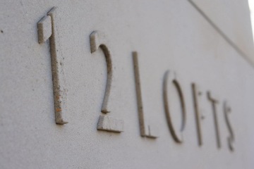 Nápis "12 Lofts" na betonové stěně.