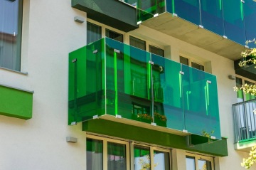 Zelená skleněná zábradlí balkónů moderního bytového domu Tesla Vršovice.