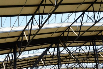 Ocelová střešní konstrukce Kaufland Podbaba s prosklenými panely a podpůrnými trámy.