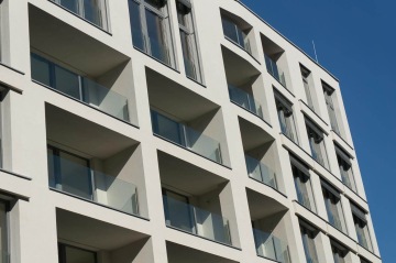 Moderní bytový dům BD Port Karolína, Praha s balkony a velkými okny pod modrou oblohou.