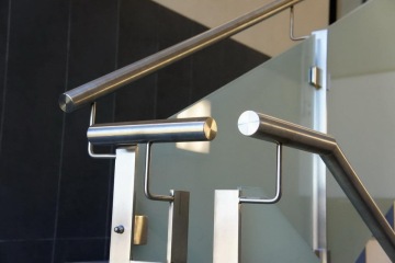 Vnitřní nerezové zábradlí na schodišti s moderním designem a skleněnou výplní.