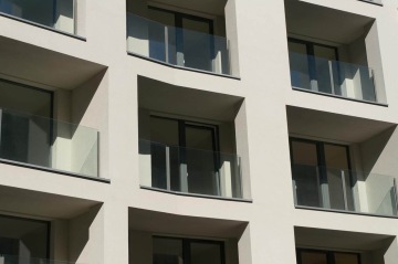 Moderní fasáda bytového domu BD Port Karolína, Praha s balkony z čirého skla.