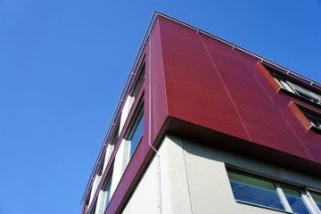 Moderní budova VTP Roztoky s červenými a bílými fasádami proti modré obloze.