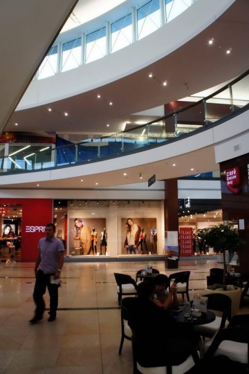 Nákupní centrum Galerie Harfa s kavárnou, kolemjdoucí lidé, obchod Esprit a další výlohy.