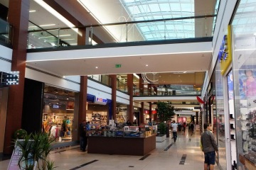 Nákupní centrum Galerie Harfa s obchody, zákazníky a prosklenou střechou.