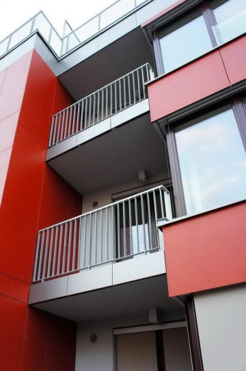 Moderní bytový dům s kovovým venkovním zábradlím balkonů a teras.