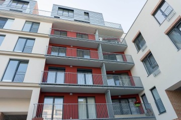 Moderní bytový dům s balkony s vnějším kovovým zábradlím.