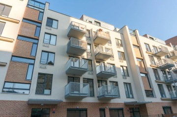 Moderní bytový dům s balkony s vnějším kovovým zábradlím.