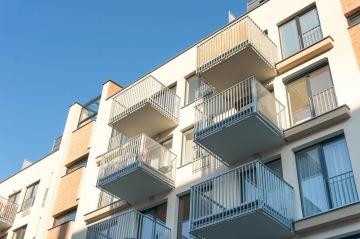 Moderní bytový dům s balkony s vnějším kovovým zábradlím.