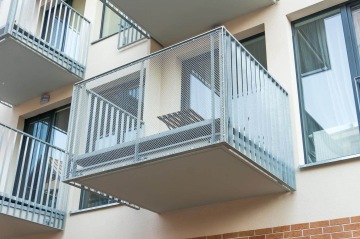 Moderní balkon s vnějším kovovým zábradlím.