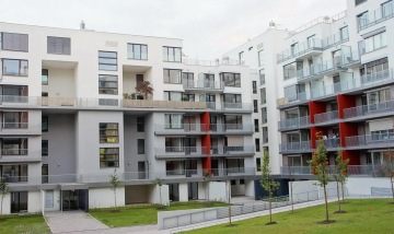 Moderní bytový dům s venkovním zábradlím balkonů a teras s příčkovými výplněmi.