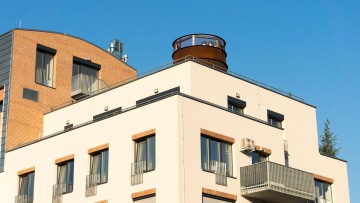 Moderní bytový dům s balkony s vnějším kovovým zábradlím.