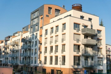 Moderní bytový dům s balkony s vnějším kovovým zábradlím.