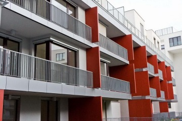 Moderní bytový dům s venkovním zábradlím balkonů a teras s příčkovými výplněmi.