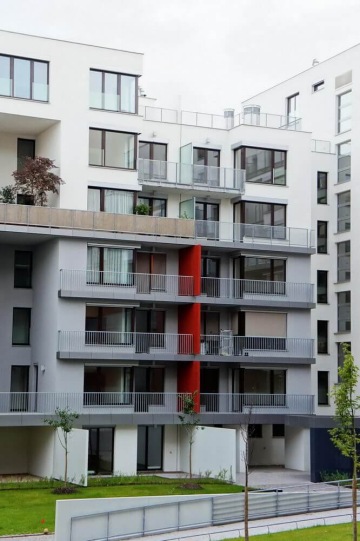 Moderní bytový dům s venkovním zábradlím balkonů a teras s příčkovými výplněmi.